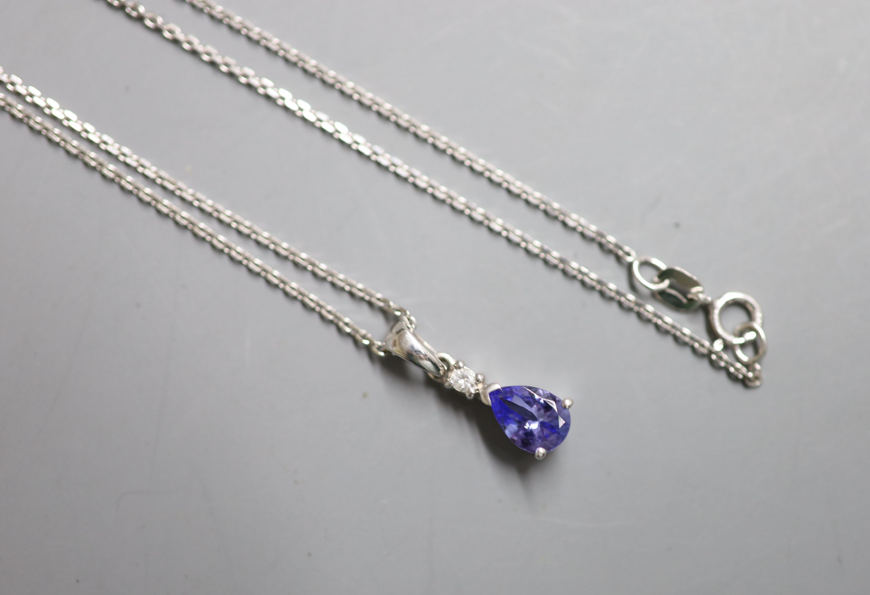 A modern 9ct white gold, tanzanite and diamond chip set drop pendant, 10mm, on a 9ct white gold fine link chain, 44cm,.